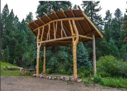 Handcrafted log pergola stage by the water